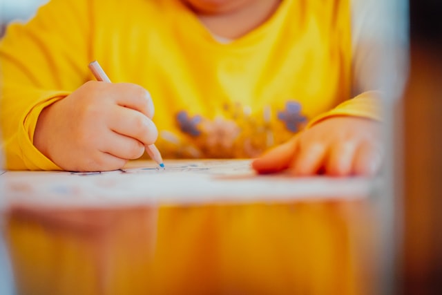 child in yellow shirt drawing a picture