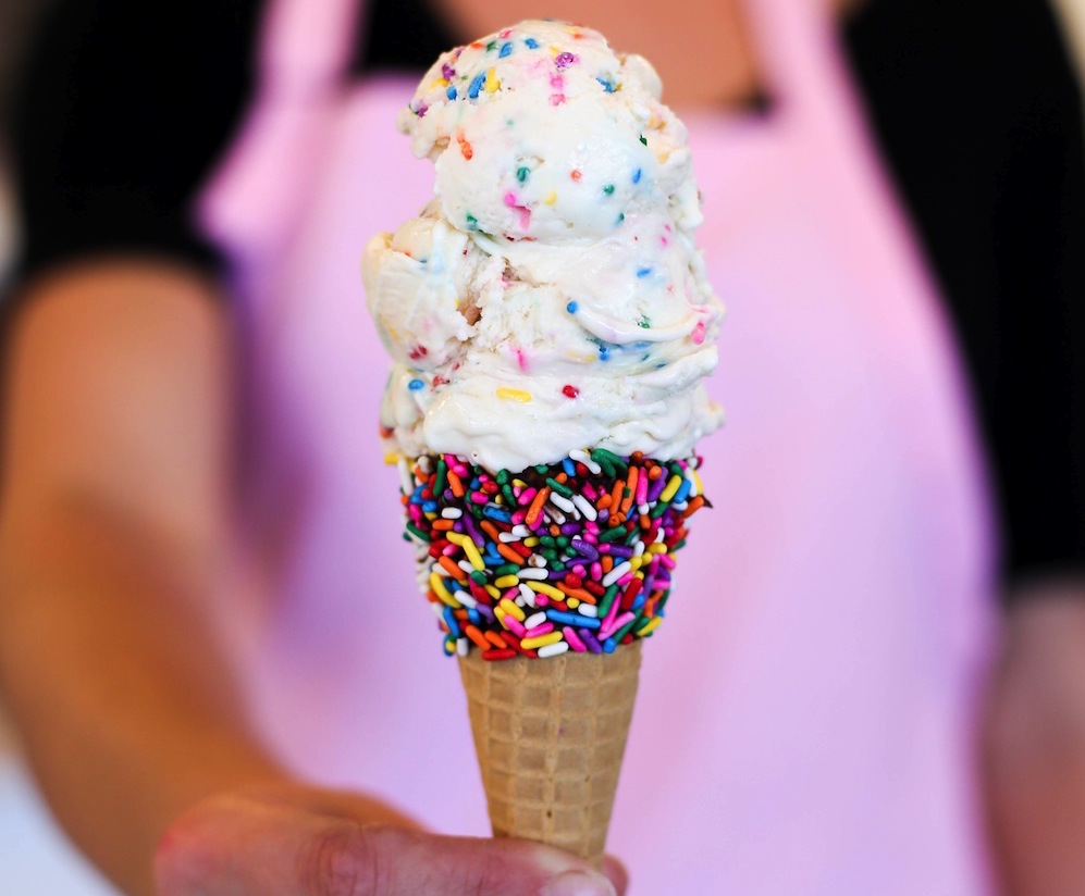woman in pink apron handing ice cream cone
